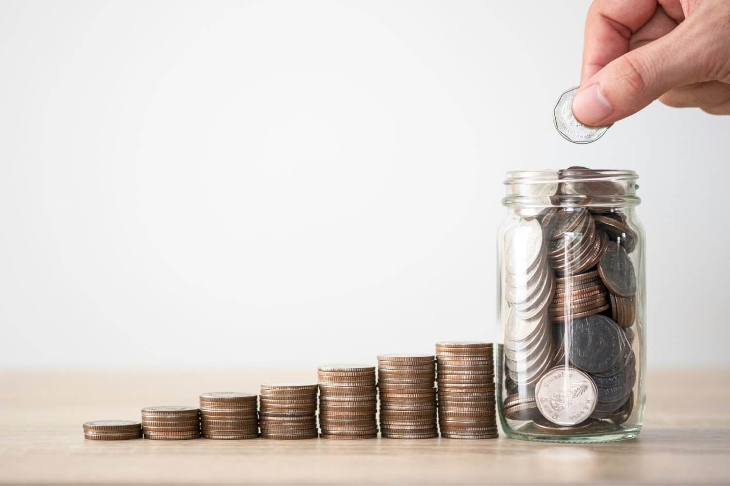 Hand putting coin to saving jar